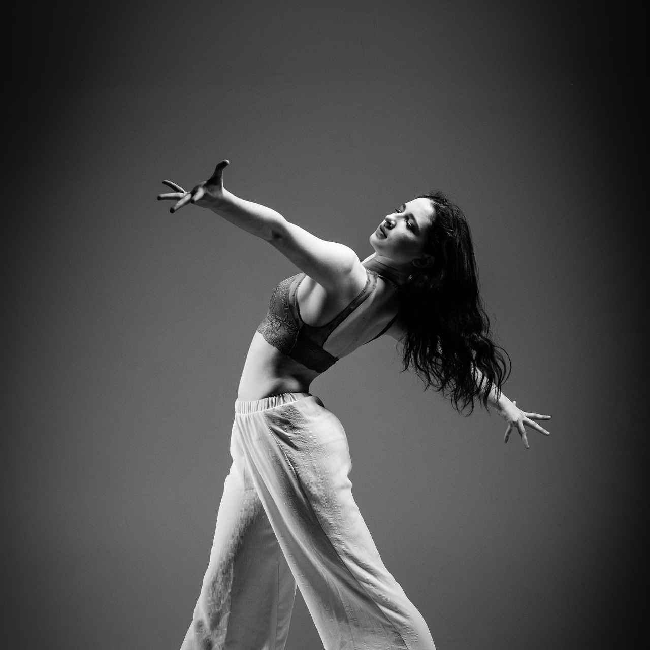 Black and white photo of a women performing modern dance on a dark background.